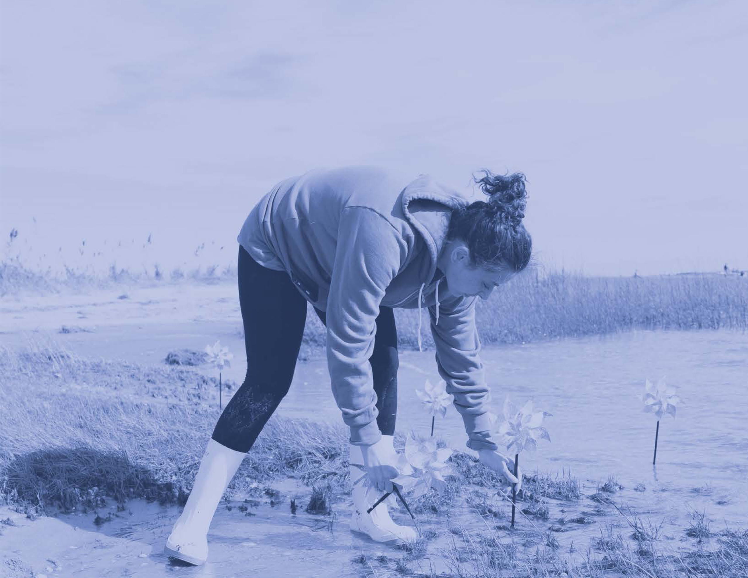 Woman in boots outside bending over with pinwheel